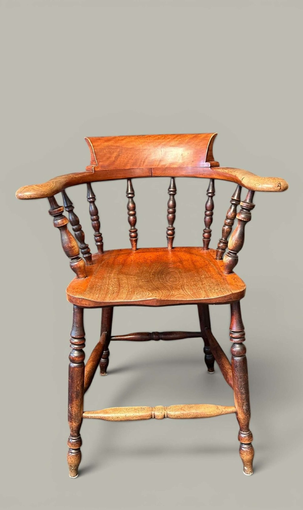 An antique alder wood Windsor captains chair featuring turned spindles, a contoured saddle seat, and high turned legs joined by stretchers. View XI