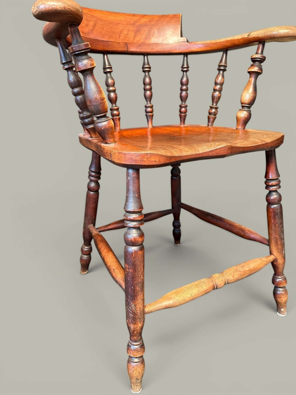 An antique alder wood Windsor captains chair featuring turned spindles, a contoured saddle seat, and high turned legs joined by stretchers. View XII