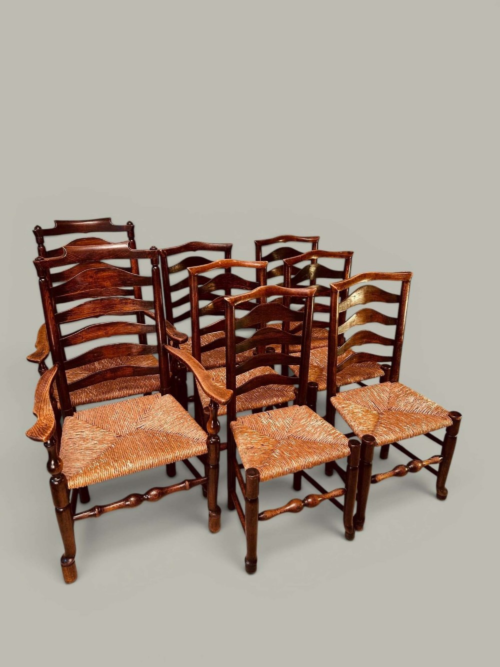 A set of dark brown ladder back dining chairs featuring woven rush seats, curved horizontal slats, and turned stretcher rails. View II