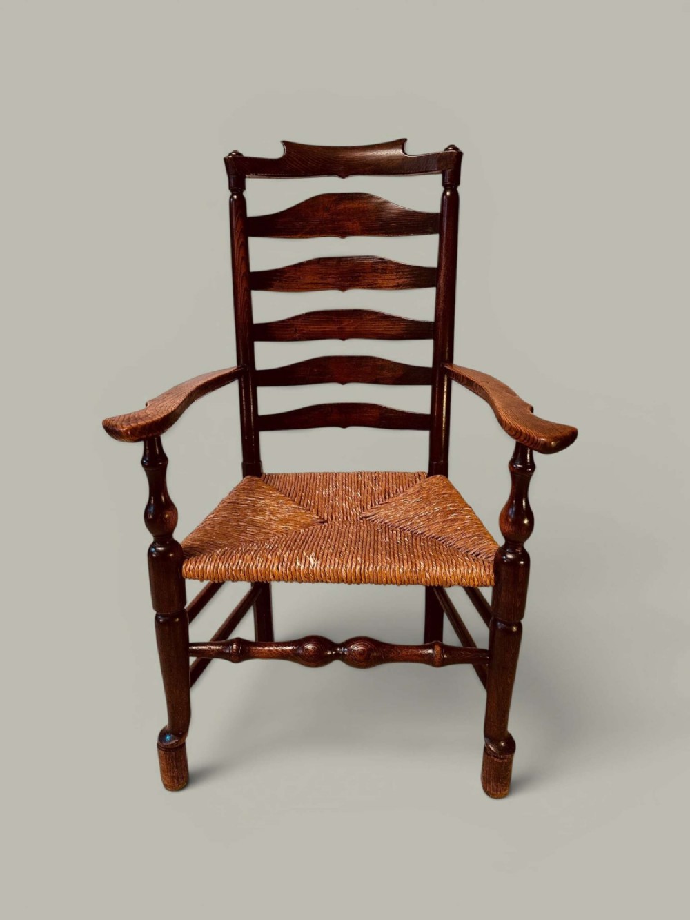 A set of dark brown ladder back dining chairs featuring woven rush seats, curved horizontal slats, and turned stretcher rails. View IV