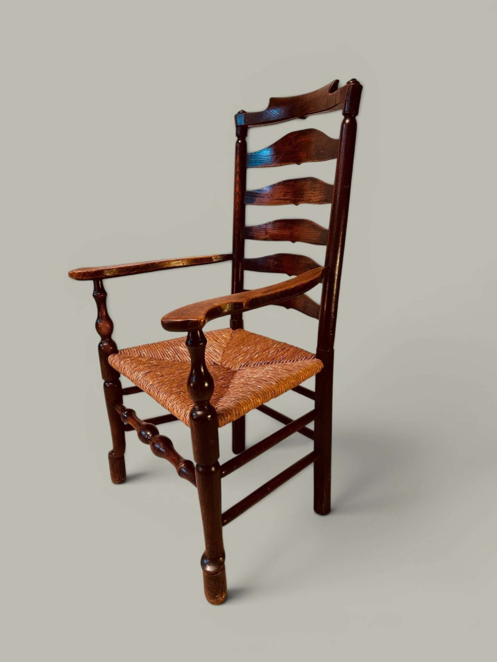 A set of dark brown ladder back dining chairs featuring woven rush seats, curved horizontal slats, and turned stretcher rails. View V