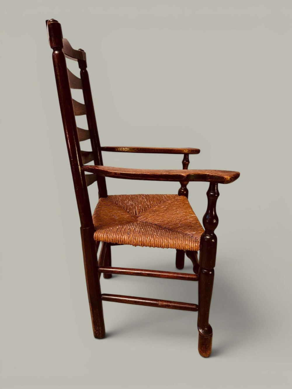 A set of dark brown ladder back dining chairs featuring woven rush seats, curved horizontal slats, and turned stretcher rails. View VIII