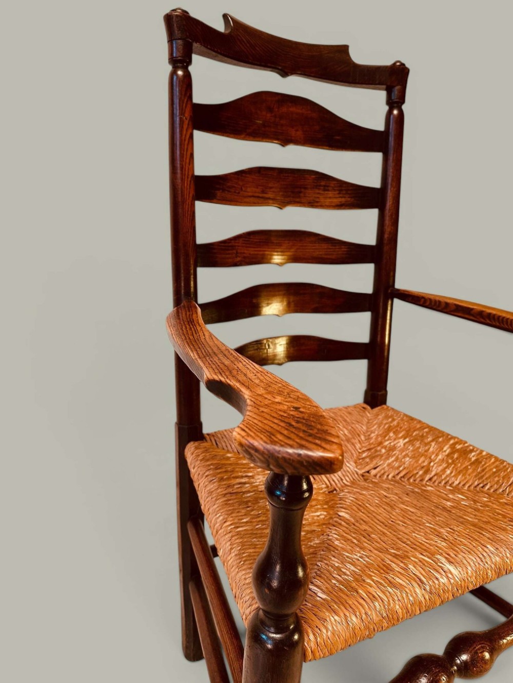 A set of dark brown ladder back dining chairs featuring woven rush seats, curved horizontal slats, and turned stretcher rails. View IX