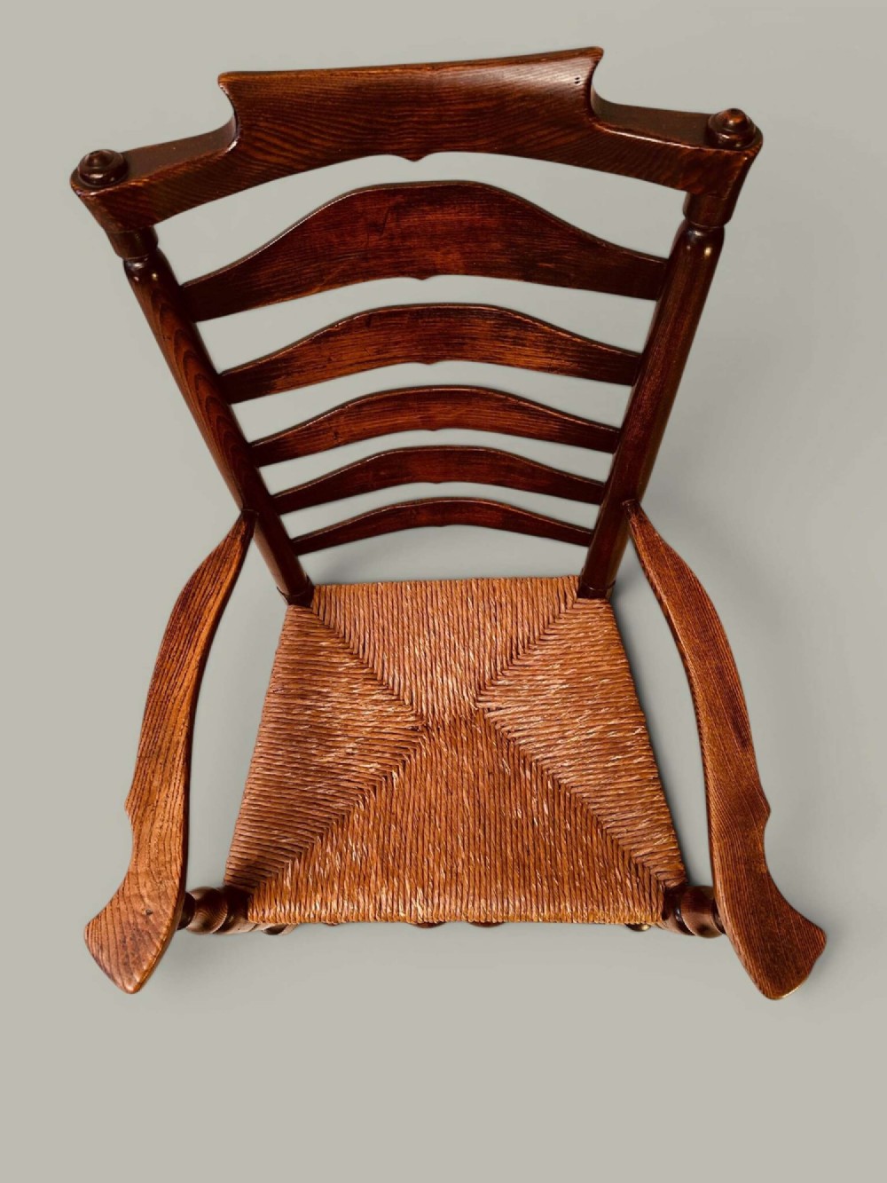 A set of dark brown ladder back dining chairs featuring woven rush seats, curved horizontal slats, and turned stretcher rails. View XI