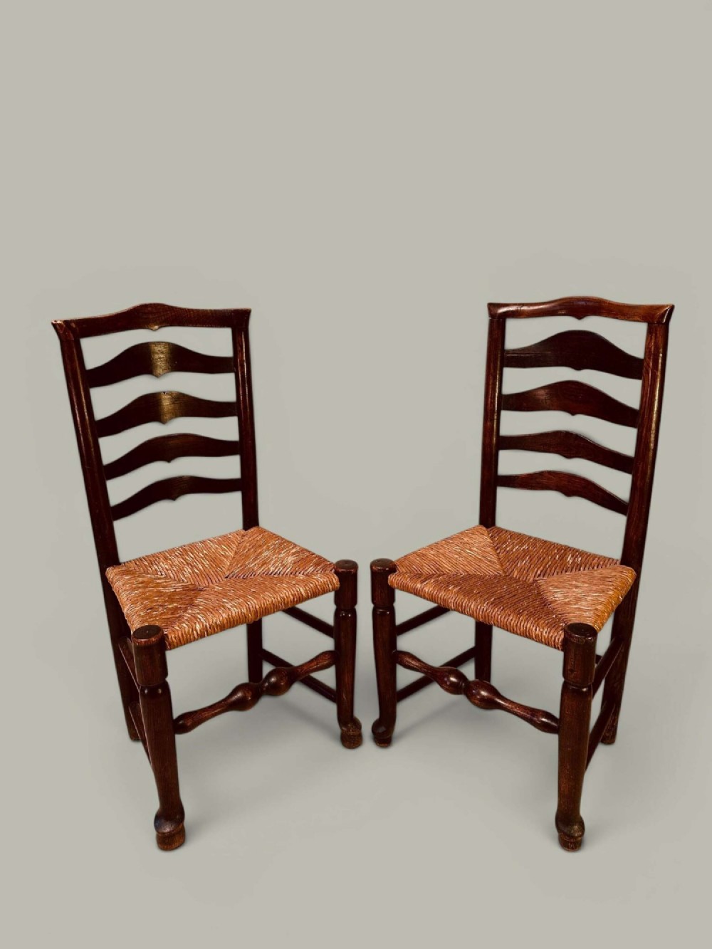 A set of dark brown ladder back dining chairs featuring woven rush seats, curved horizontal slats, and turned stretcher rails. View XIII