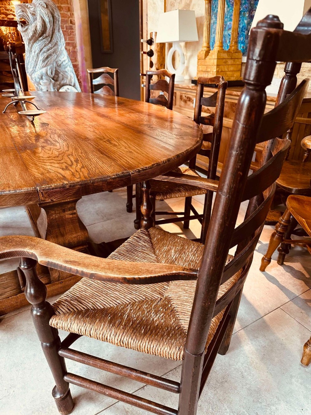 A set of dark brown ladder back dining chairs featuring woven rush seats, curved horizontal slats, and turned stretcher rails. View XIV