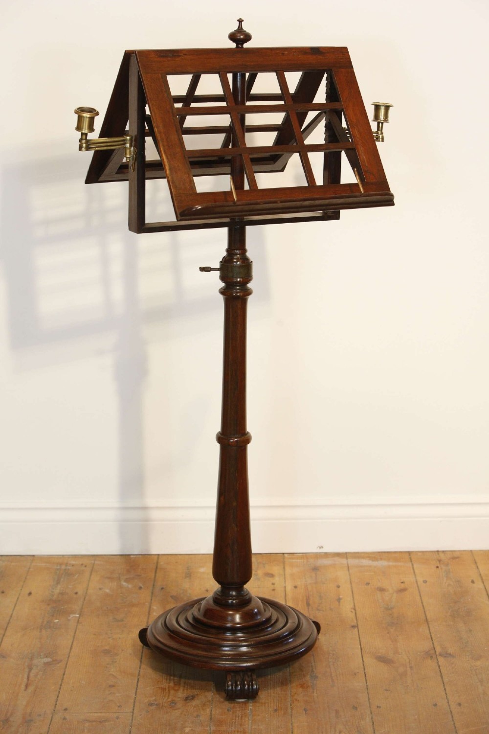 A 19th-century rosewood duet music stand with a double-sided lattice desk, brass candle sconces, an adjustable turned column, and a circular stepped base. View IV
