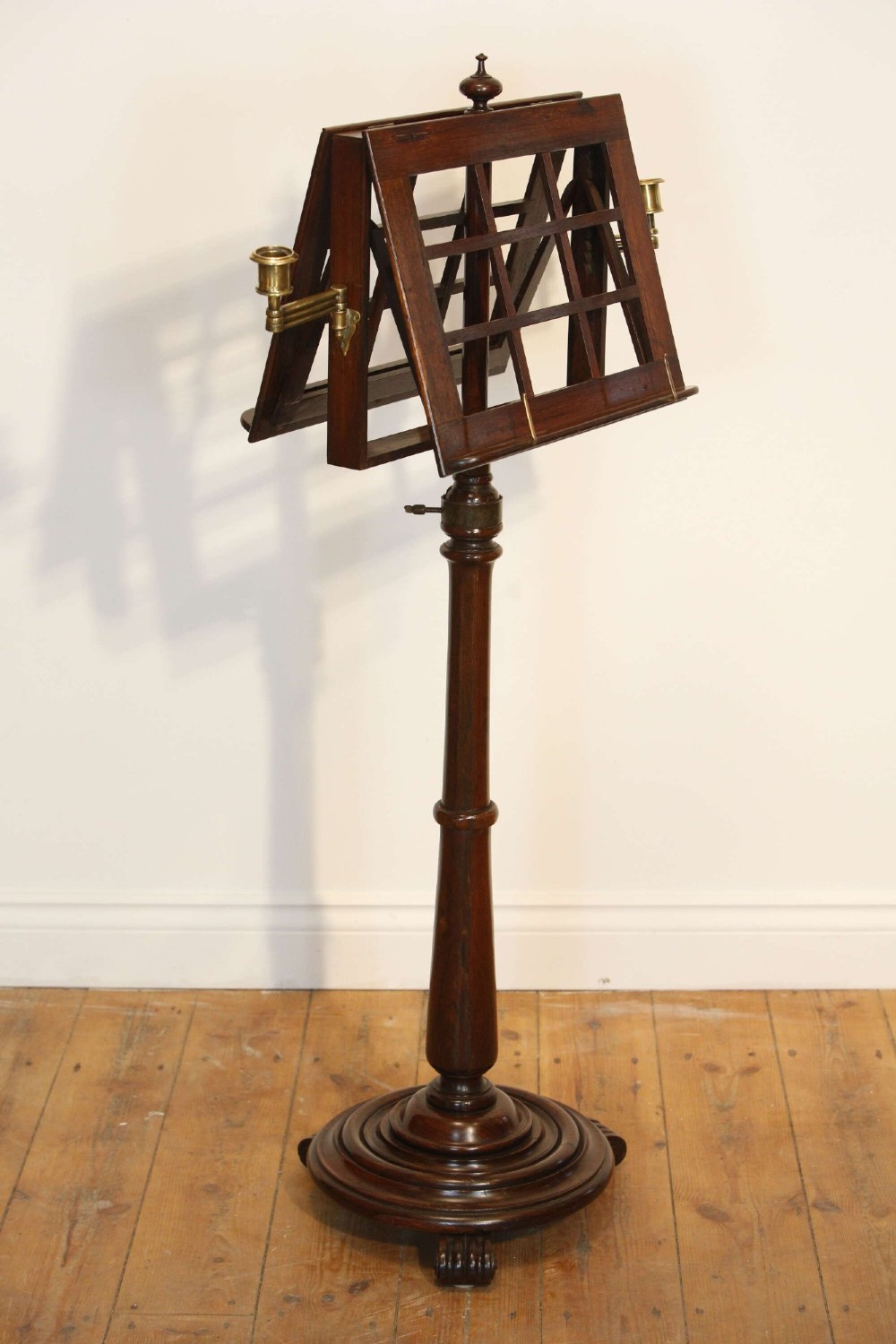 A 19th-century rosewood duet music stand with a double-sided lattice desk, brass candle sconces, an adjustable turned column, and a circular stepped base. View X