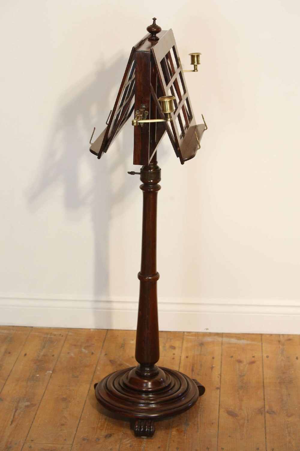 A 19th-century rosewood duet music stand with a double-sided lattice desk, brass candle sconces, an adjustable turned column, and a circular stepped base. View XI