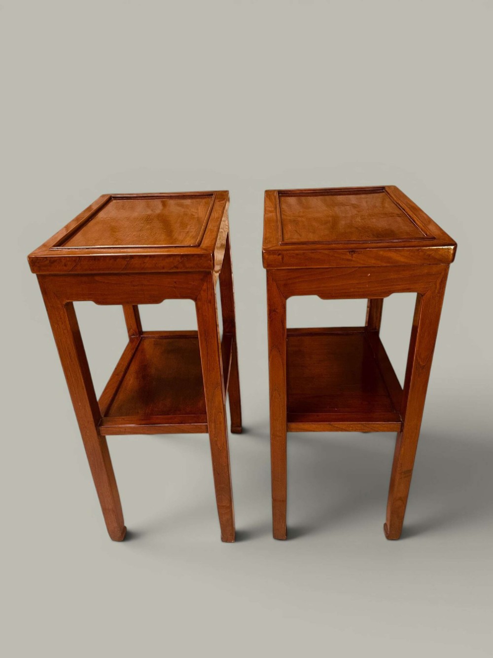A pair of warm brown Chinese hardwood side tables featuring raised top borders, lower shelves, and straight square legs. View VI