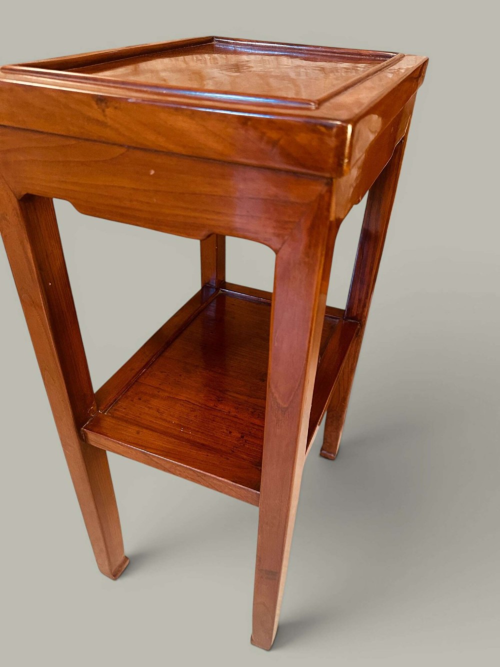 A pair of warm brown Chinese hardwood side tables featuring raised top borders, lower shelves, and straight square legs. View X