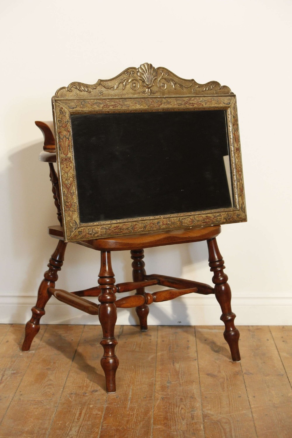 A 19th-century rectangular cushion wall mirror featuring an embroidered tapestry border, an ornamental gilt crest with a shell motif, and a glass plate.