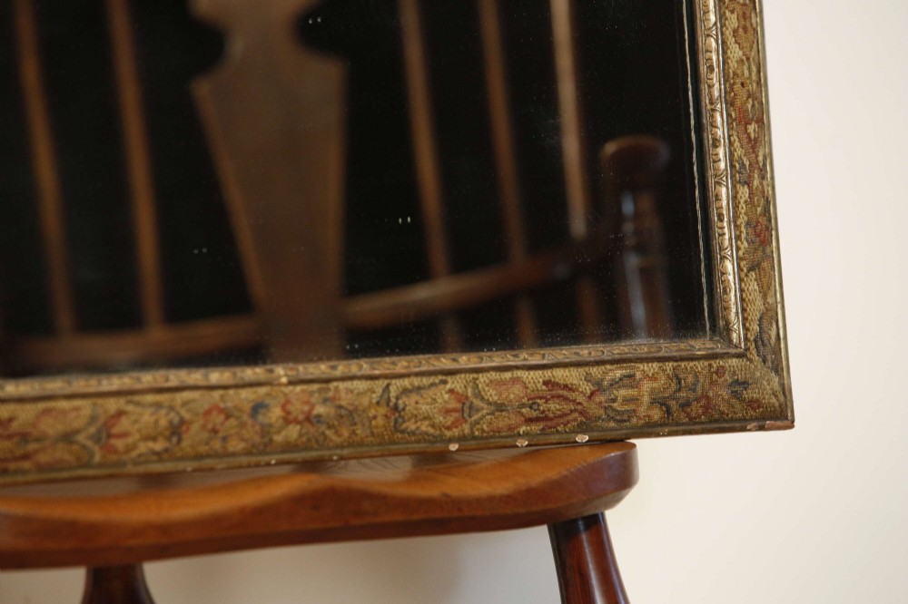 A 19th-century rectangular cushion wall mirror featuring an embroidered tapestry border, an ornamental gilt crest with a shell motif, and a glass plate. View V