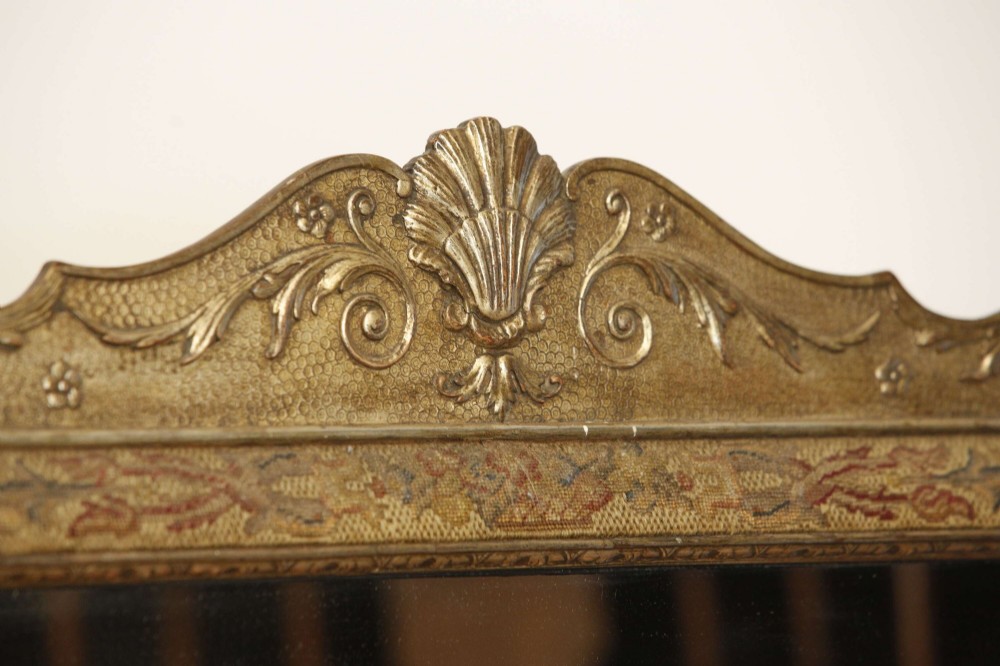 A 19th-century rectangular cushion wall mirror featuring an embroidered tapestry border, an ornamental gilt crest with a shell motif, and a glass plate. View VI