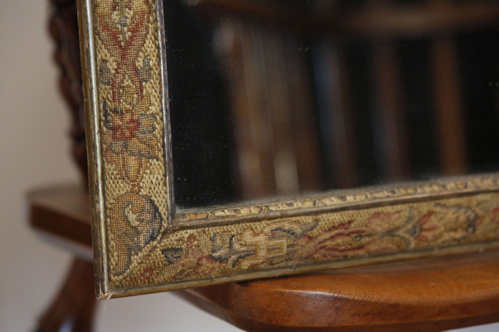 A 19th-century rectangular cushion wall mirror featuring an embroidered tapestry border, an ornamental gilt crest with a shell motif, and a glass plate. View VII