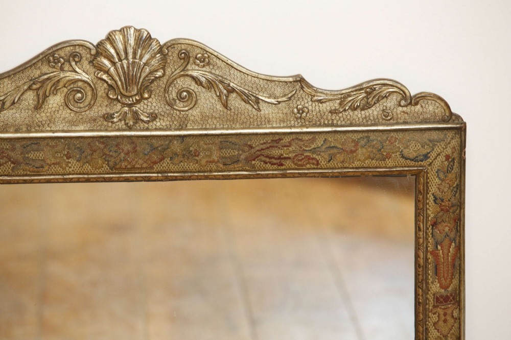 A 19th-century rectangular cushion wall mirror featuring an embroidered tapestry border, an ornamental gilt crest with a shell motif, and a glass plate. View XI