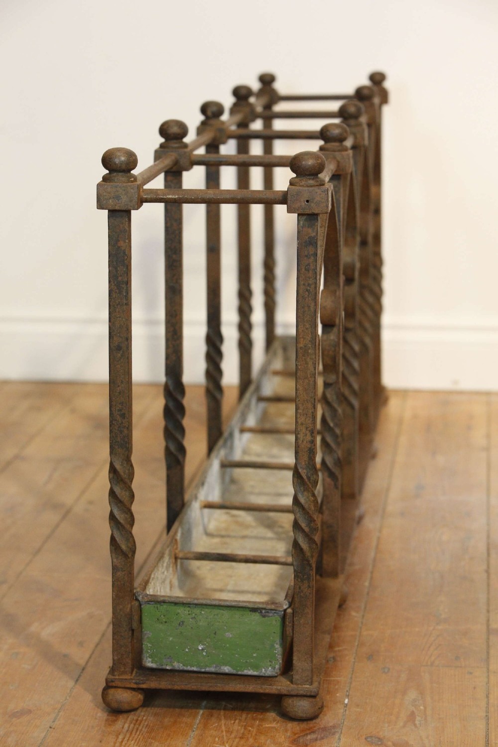 A rectangular Victorian Gothic Revival wrought iron umbrella stand featuring pointed tracery arches, twisted corner posts with ball finials, and a removable green metal drip tray. View IV