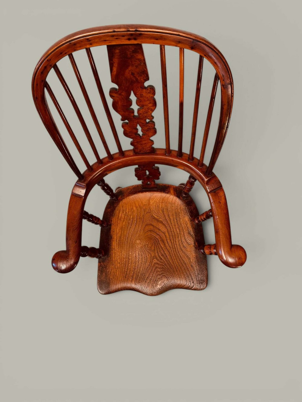 A pair of 19th-century yew and elm Windsor armchairs featuring curved hoop backs, pierced central splats, broad armrests, and turned legs. View V