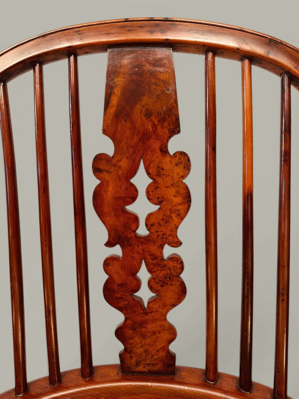 A pair of 19th-century yew and elm Windsor armchairs featuring curved hoop backs, pierced central splats, broad armrests, and turned legs. View VI
