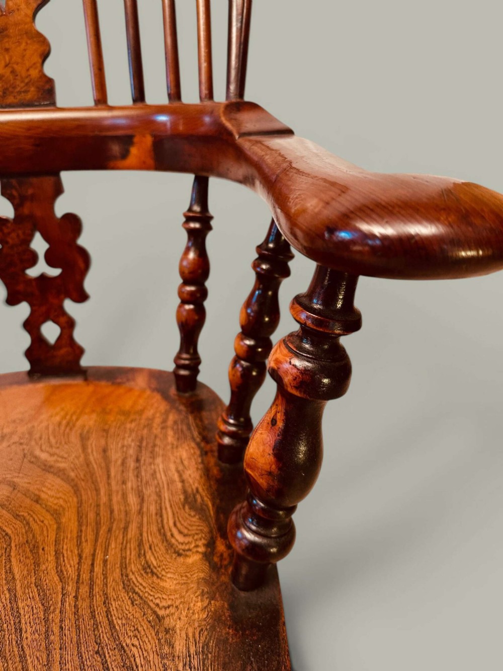 A pair of 19th-century yew and elm Windsor armchairs featuring curved hoop backs, pierced central splats, broad armrests, and turned legs. View X