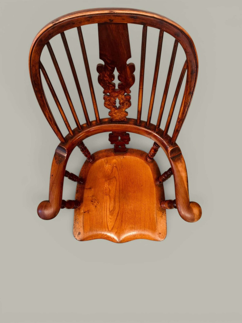 A pair of 19th-century yew and elm Windsor armchairs featuring curved hoop backs, pierced central splats, broad armrests, and turned legs. View XV