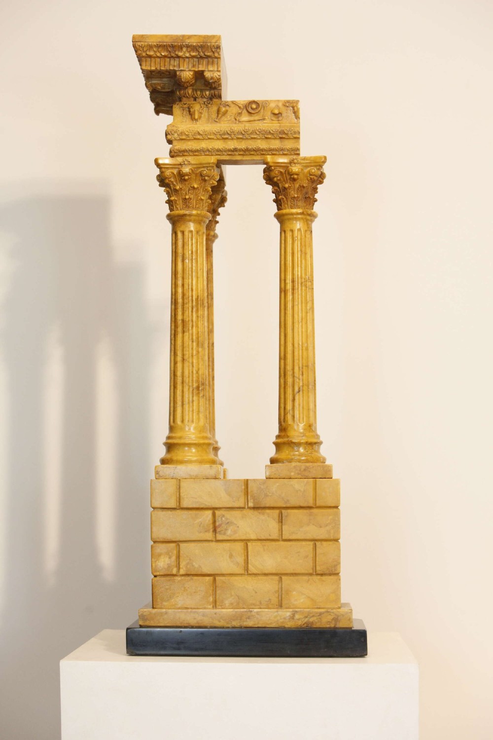 A 19th-century Grand Tour sienna marble architectural model depicting three fluted Corinthian columns of the Temple of Vespasian mounted on a black marble base. View VI