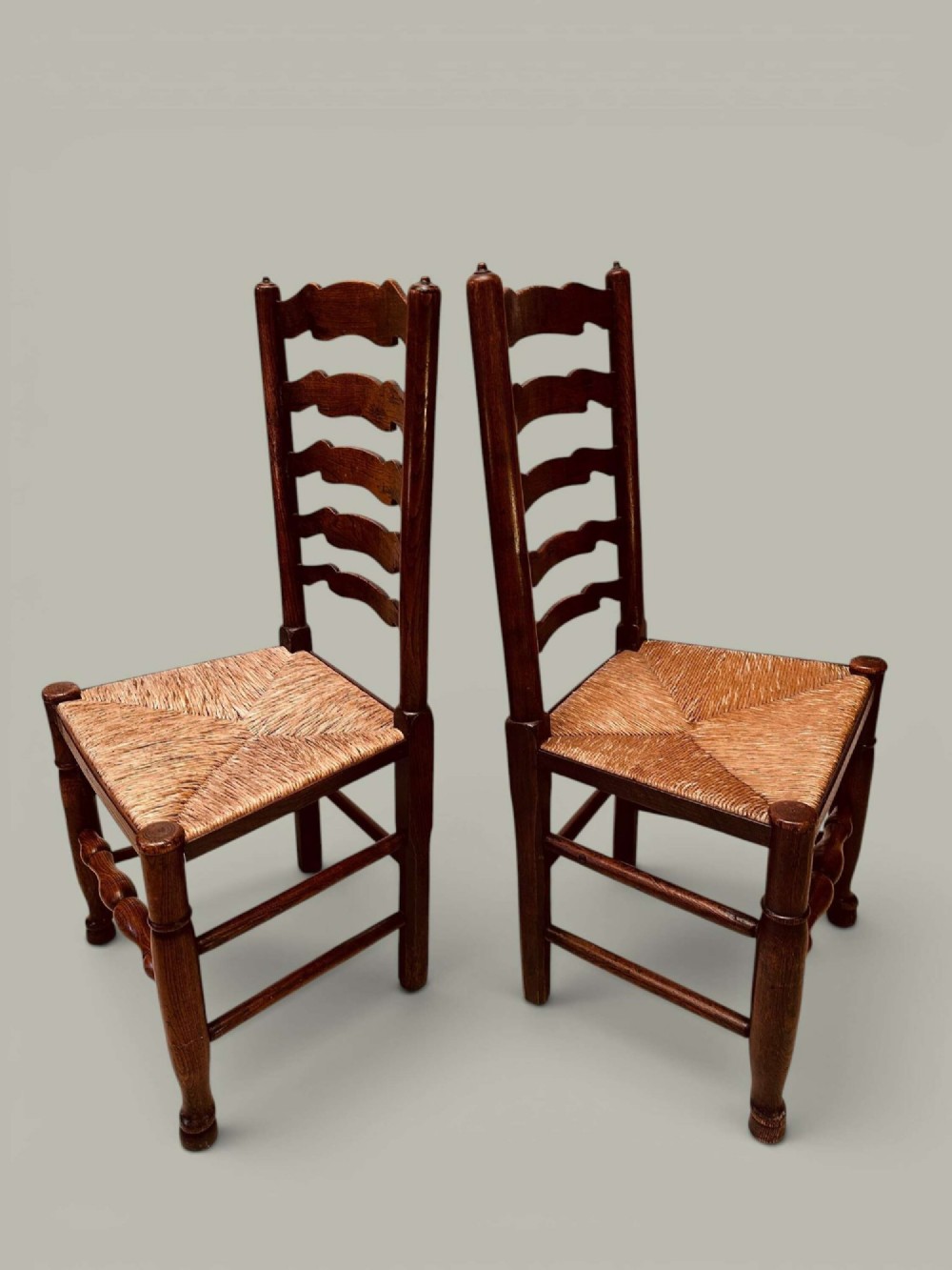A set of eight antique ash dining chairs featuring wavy ladder backs, turned stretchers, and woven rush seats, comprising six side chairs and two carver armchairs. View IV