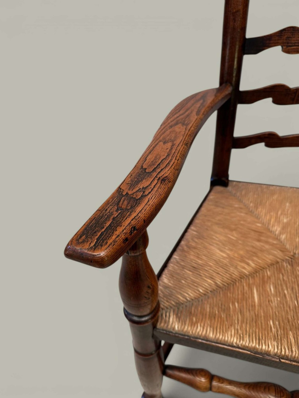 A set of eight antique ash dining chairs featuring wavy ladder backs, turned stretchers, and woven rush seats, comprising six side chairs and two carver armchairs. View X
