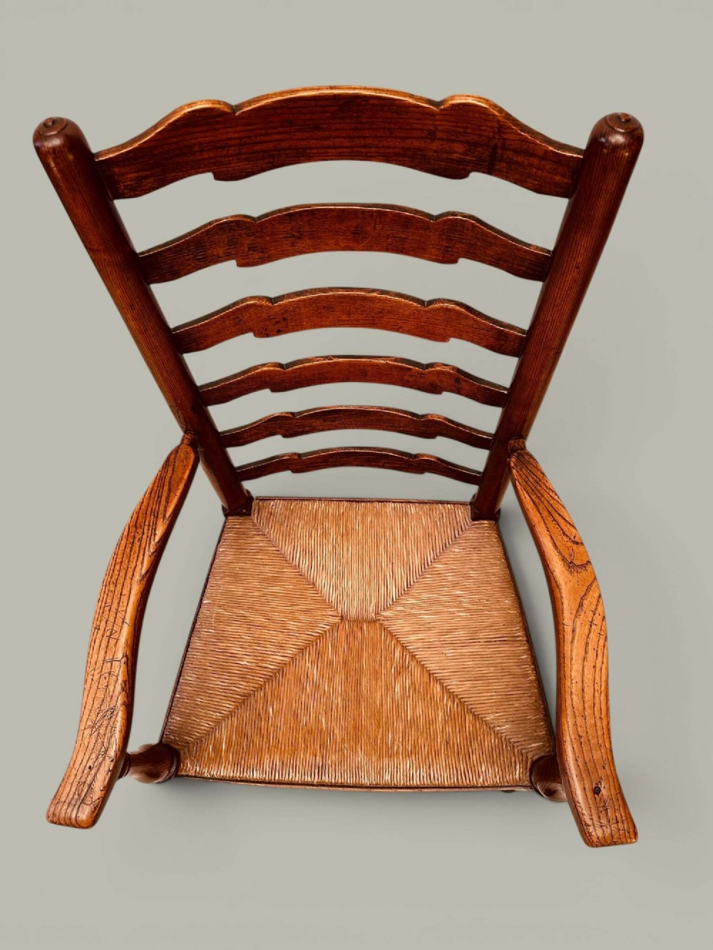 A set of eight antique ash dining chairs featuring wavy ladder backs, turned stretchers, and woven rush seats, comprising six side chairs and two carver armchairs. View XII