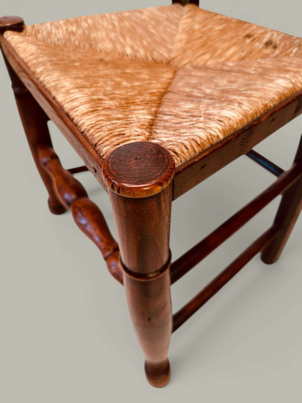 A set of eight antique ash dining chairs featuring wavy ladder backs, turned stretchers, and woven rush seats, comprising six side chairs and two carver armchairs. View XIII