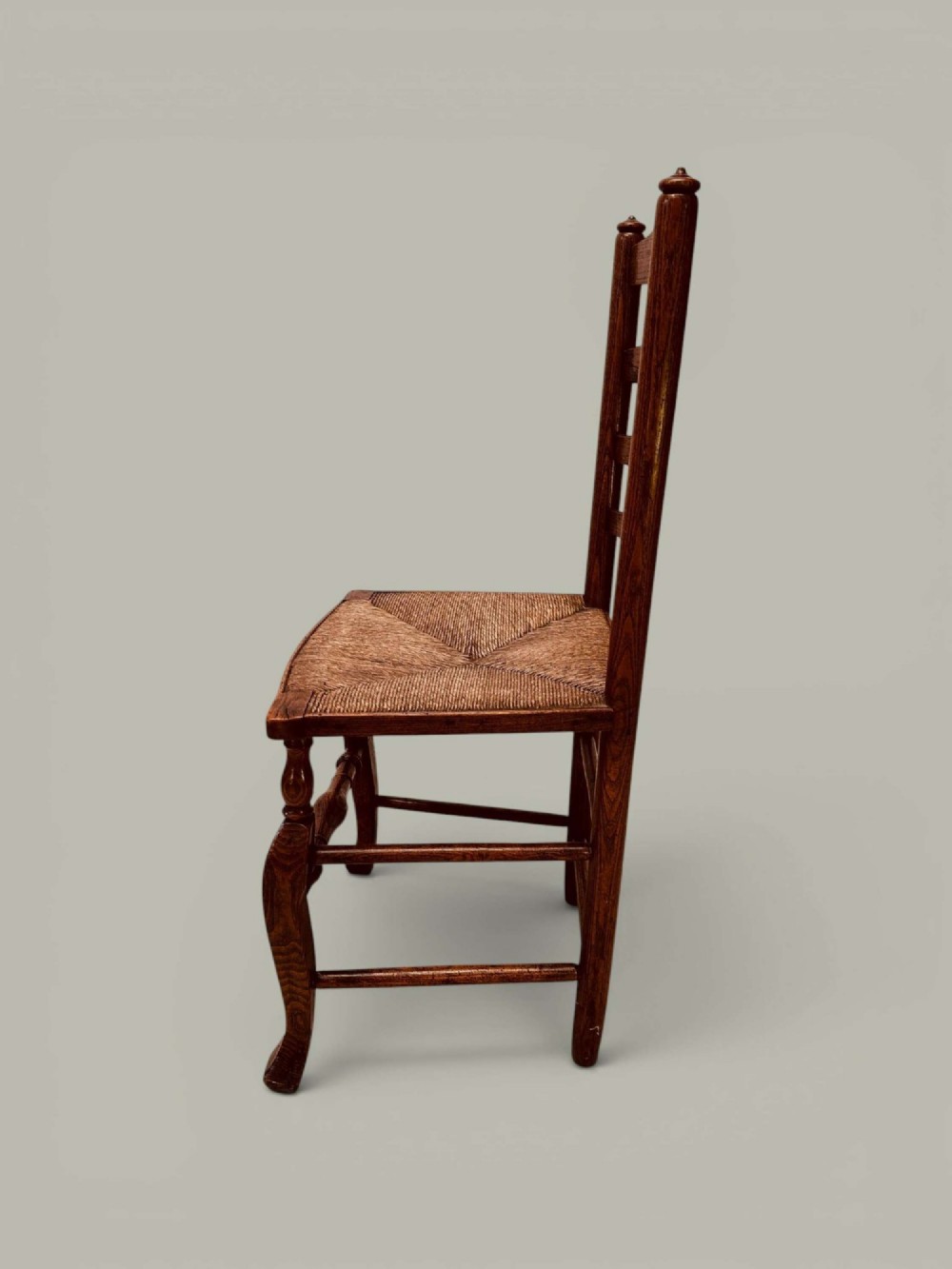A pair of antique ash ladder back side chairs featuring shaped back rungs, woven rush seats, cabriole front legs, and turned stretchers. View III