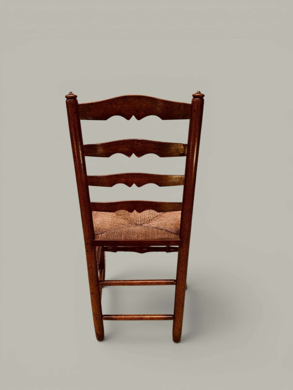 A pair of antique ash ladder back side chairs featuring shaped back rungs, woven rush seats, cabriole front legs, and turned stretchers. View IV