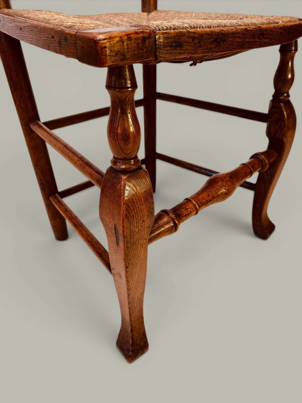 A pair of antique ash ladder back side chairs featuring shaped back rungs, woven rush seats, cabriole front legs, and turned stretchers. View VII