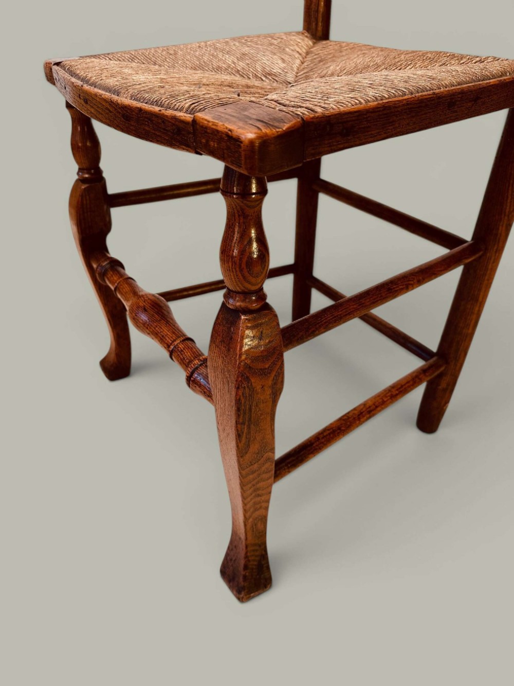 A pair of antique ash ladder back side chairs featuring shaped back rungs, woven rush seats, cabriole front legs, and turned stretchers. View VIII