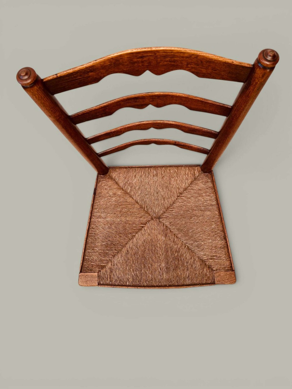 A pair of antique ash ladder back side chairs featuring shaped back rungs, woven rush seats, cabriole front legs, and turned stretchers. View X