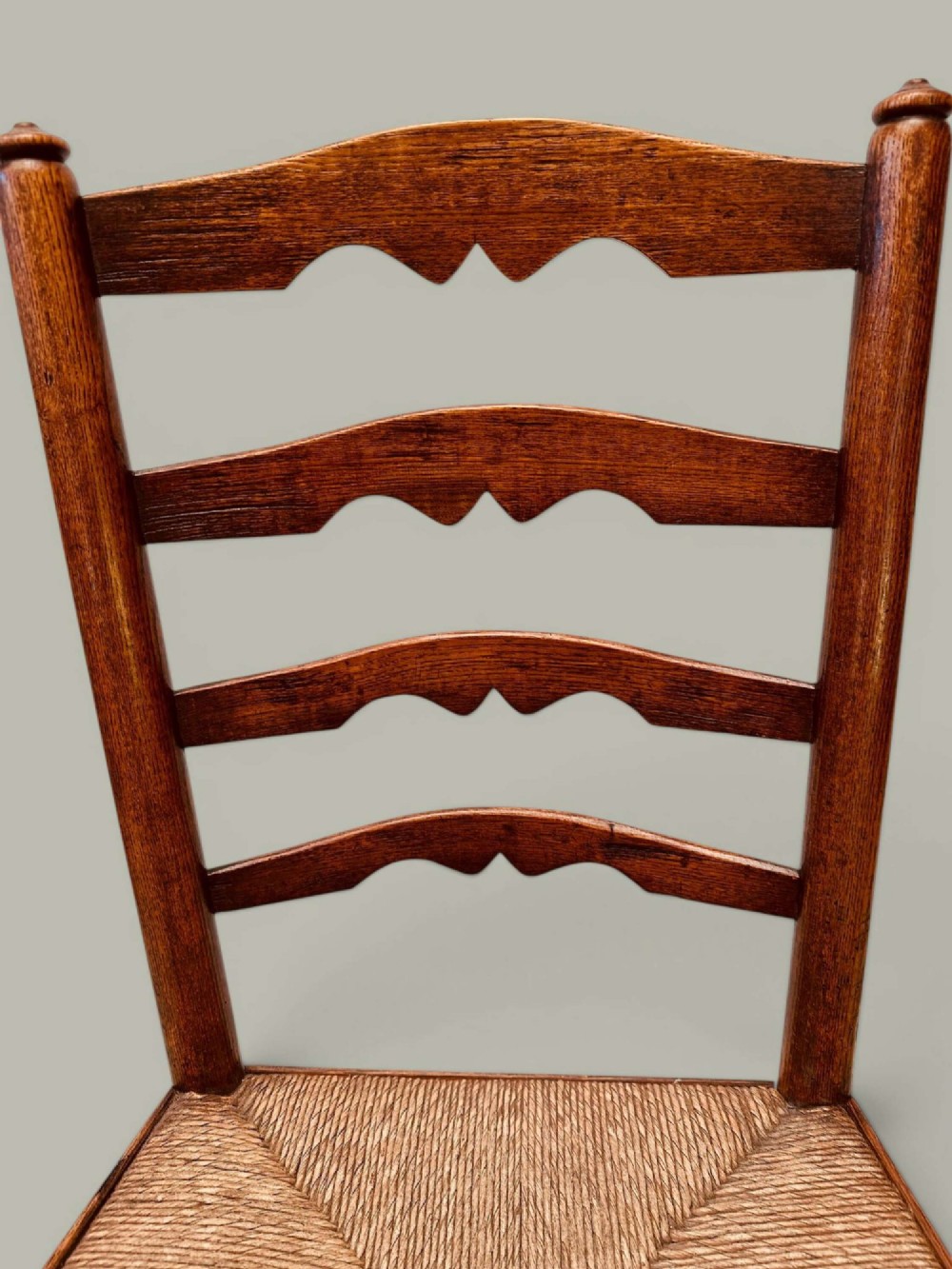 A pair of antique ash ladder back side chairs featuring shaped back rungs, woven rush seats, cabriole front legs, and turned stretchers. View XII