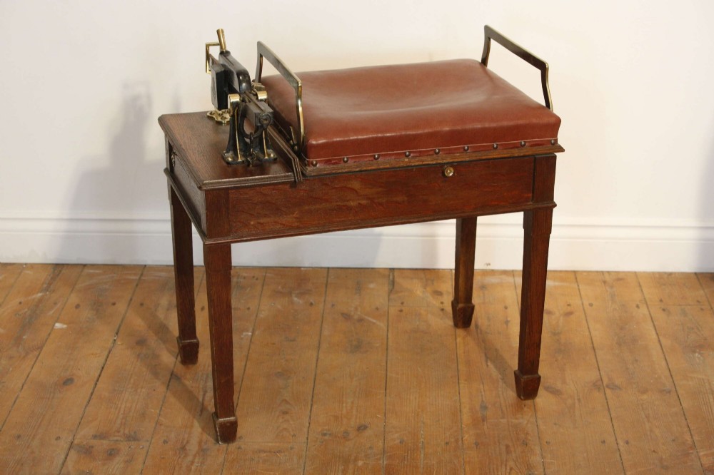 An Edwardian oak jockey scale featuring a padded brown leather seat with brass studs, brass side handles, and an integrated metal balance beam weighing mechanism.