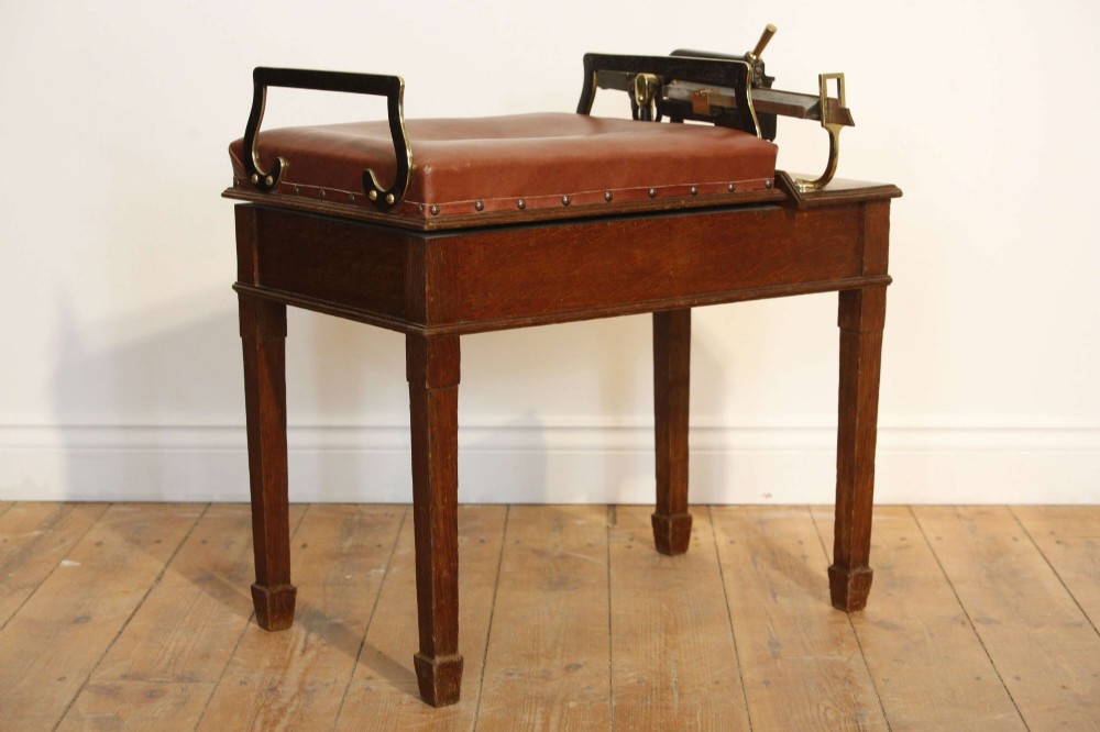 An Edwardian oak jockey scale featuring a padded brown leather seat with brass studs, brass side handles, and an integrated metal balance beam weighing mechanism. View IV
