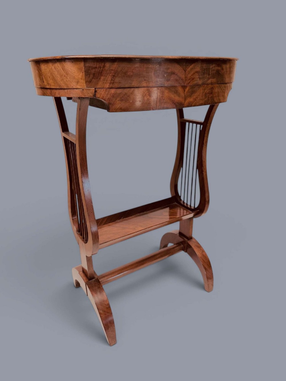 A Regency period mahogany tricoteuse table featuring a gallery top rim, lyre-shaped leg supports with vertical rods, a lower shelf, and splayed feet. View III