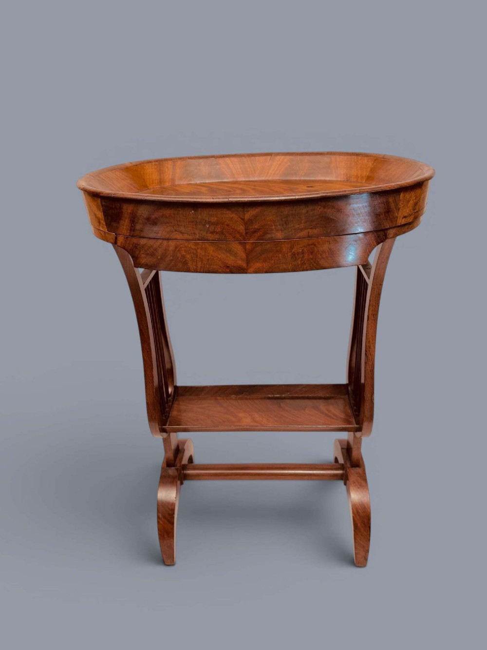 A Regency period mahogany tricoteuse table featuring a gallery top rim, lyre-shaped leg supports with vertical rods, a lower shelf, and splayed feet. View VI