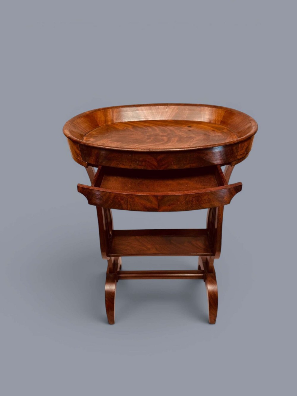 A Regency period mahogany tricoteuse table featuring a gallery top rim, lyre-shaped leg supports with vertical rods, a lower shelf, and splayed feet. View VII