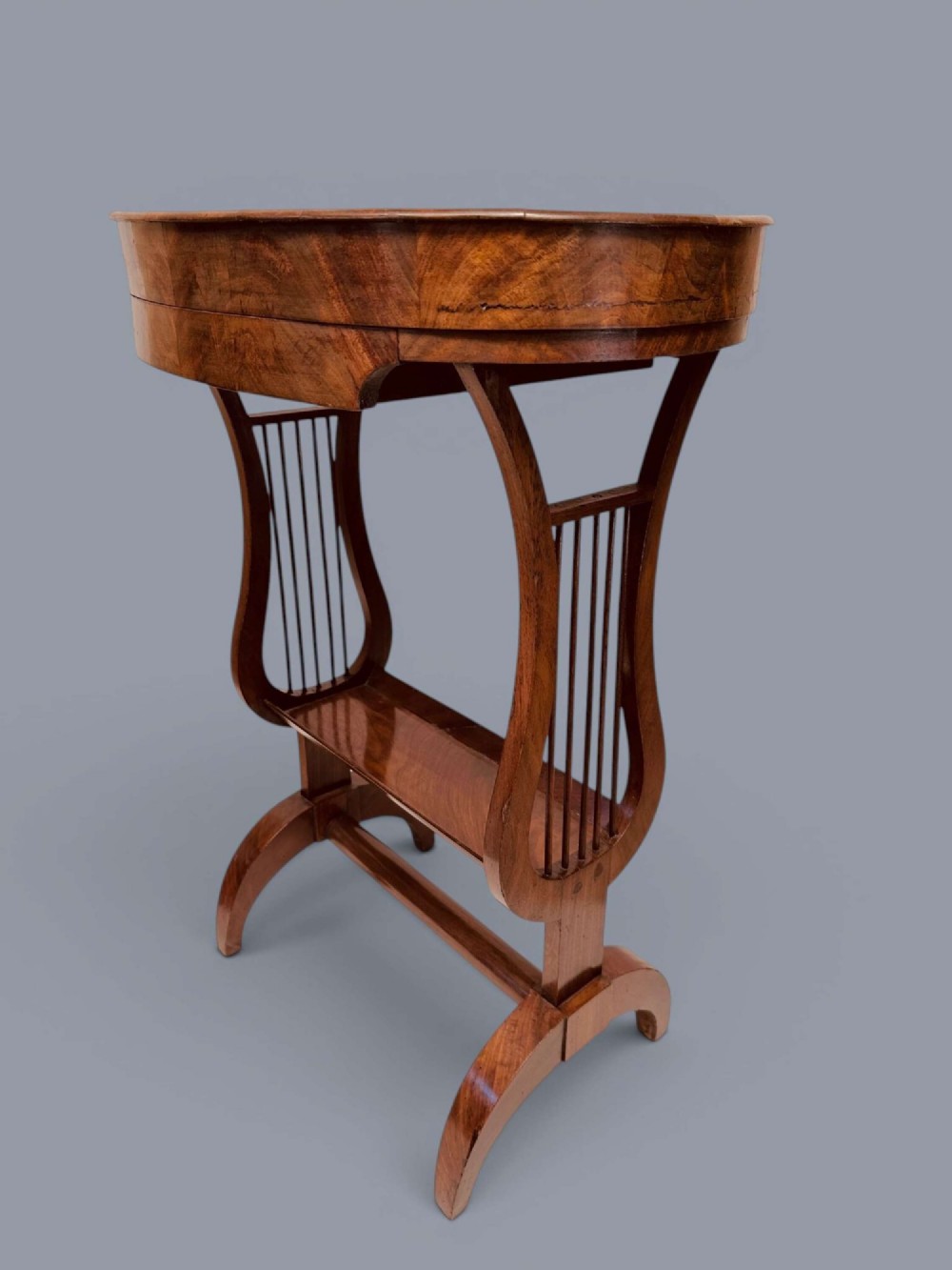 A Regency period mahogany tricoteuse table featuring a gallery top rim, lyre-shaped leg supports with vertical rods, a lower shelf, and splayed feet. View X