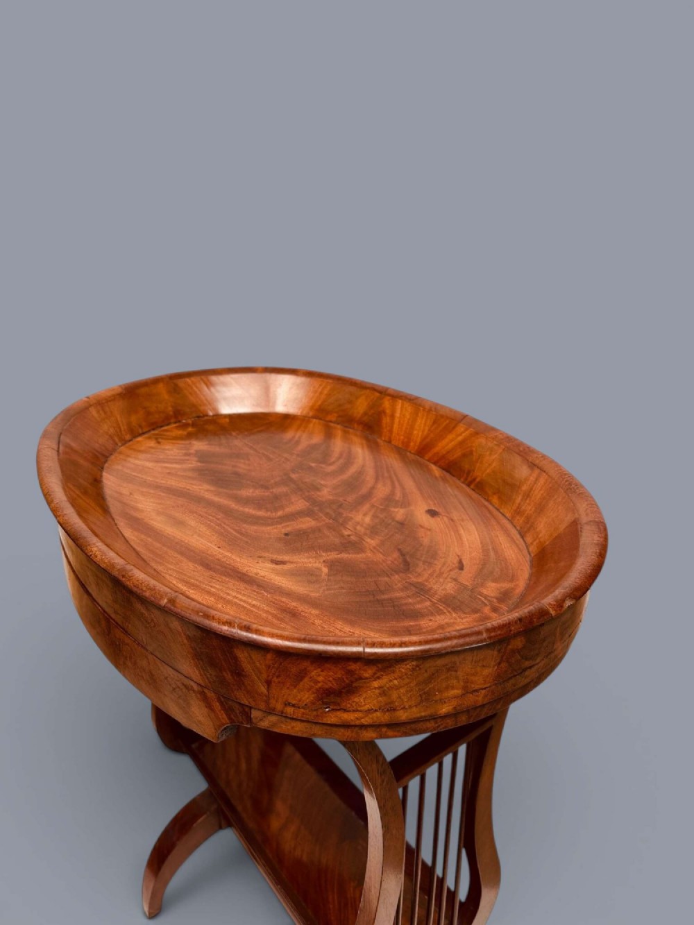 A Regency period mahogany tricoteuse table featuring a gallery top rim, lyre-shaped leg supports with vertical rods, a lower shelf, and splayed feet. View XII