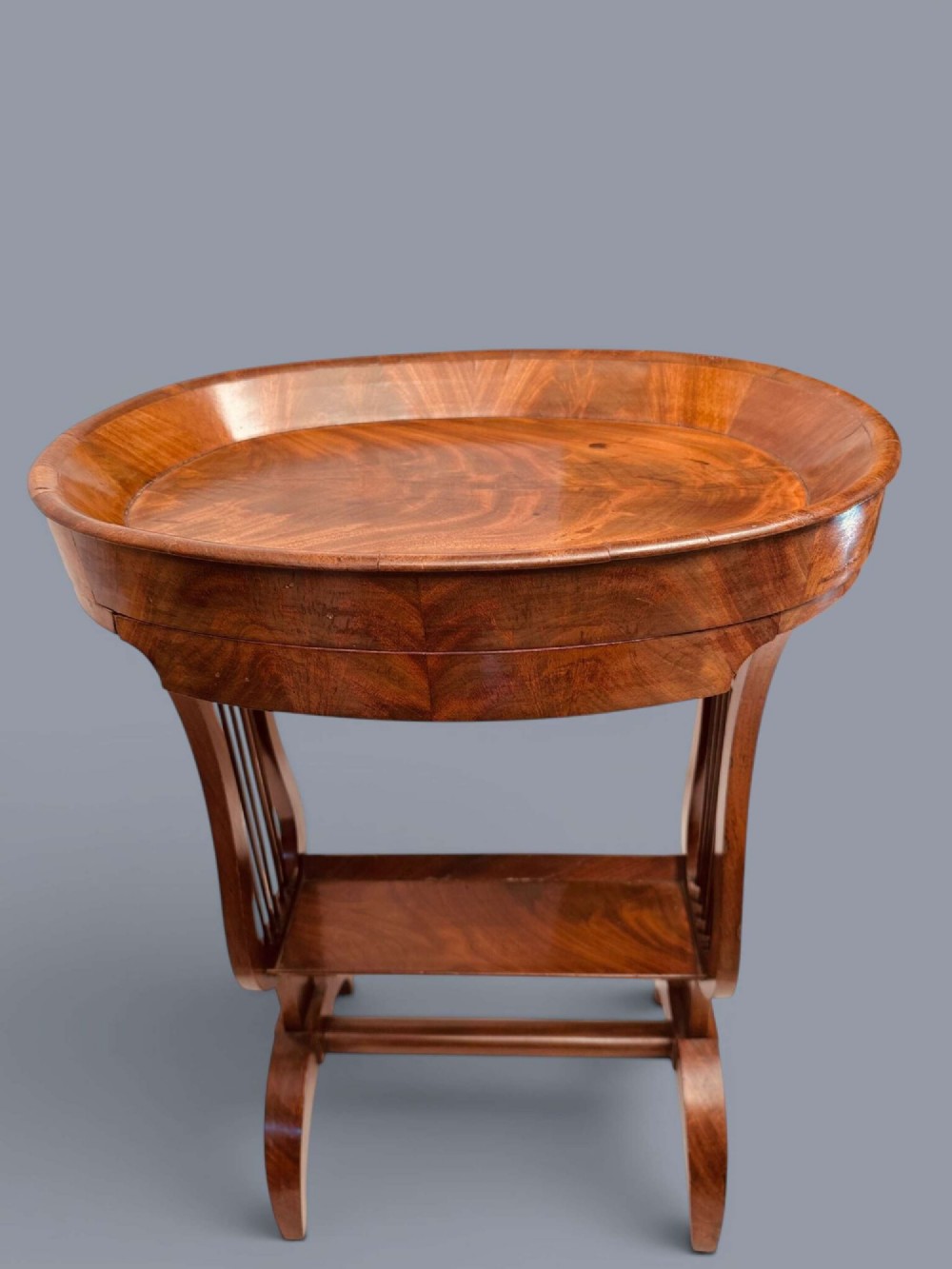 A Regency period mahogany tricoteuse table featuring a gallery top rim, lyre-shaped leg supports with vertical rods, a lower shelf, and splayed feet. View XIII