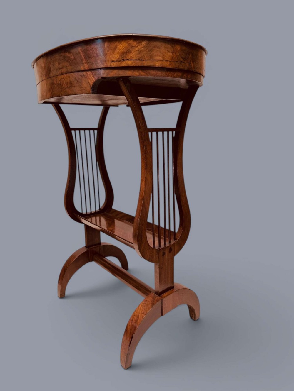 A Regency period mahogany tricoteuse table featuring a gallery top rim, lyre-shaped leg supports with vertical rods, a lower shelf, and splayed feet. View XV