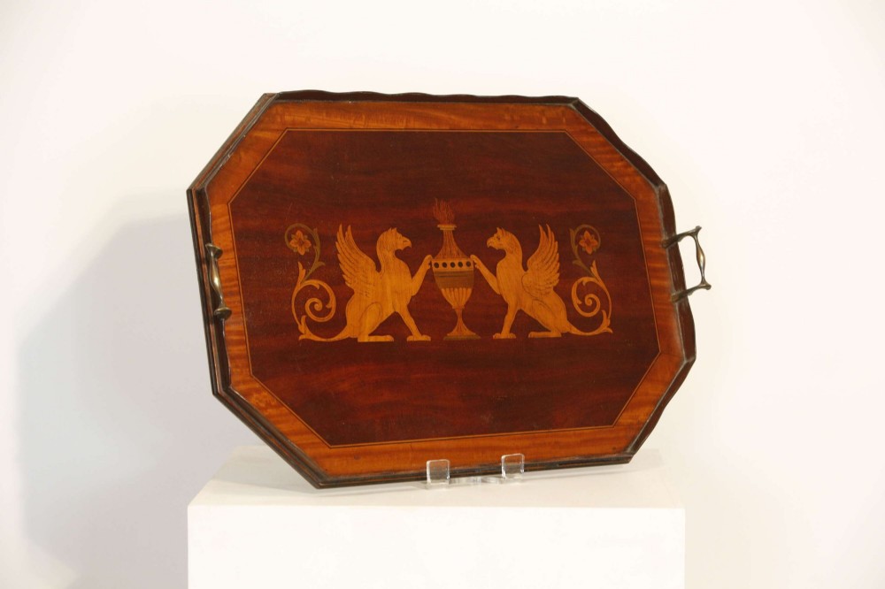 An octagonal mahogany serving tray featuring central marquetry inlay depicting twin winged griffins flanking a classical urn, with brass handles on two sides.