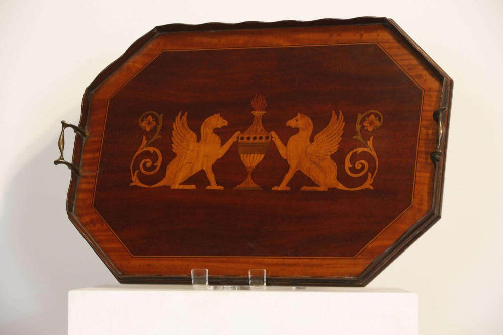 An octagonal mahogany serving tray featuring central marquetry inlay depicting twin winged griffins flanking a classical urn, with brass handles on two sides. View V