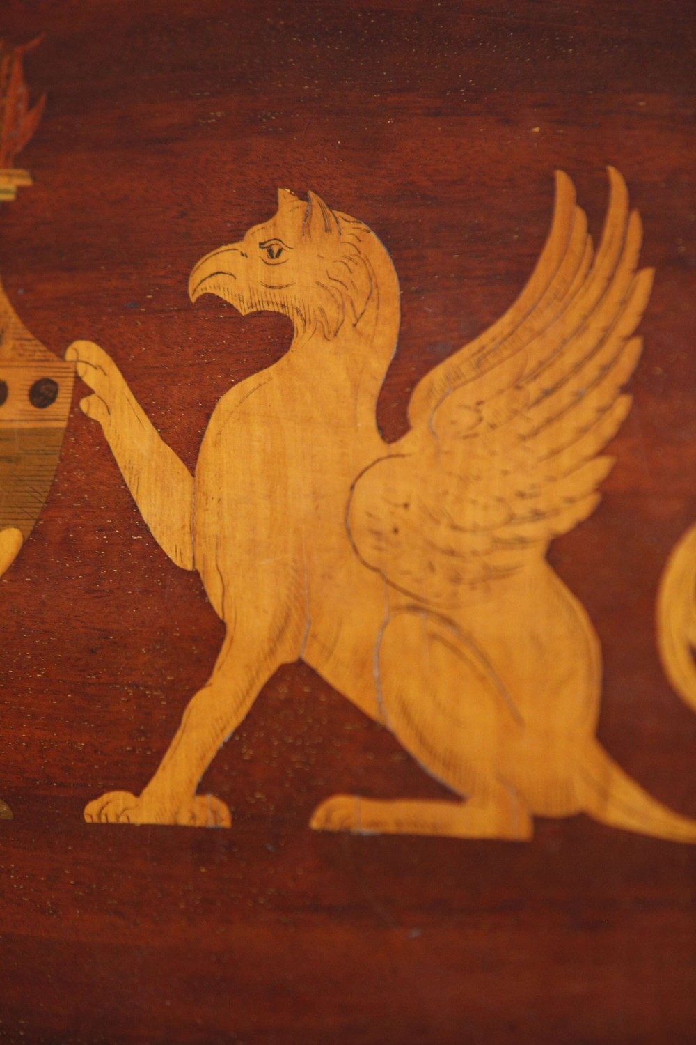 An octagonal mahogany serving tray featuring central marquetry inlay depicting twin winged griffins flanking a classical urn, with brass handles on two sides. View VII