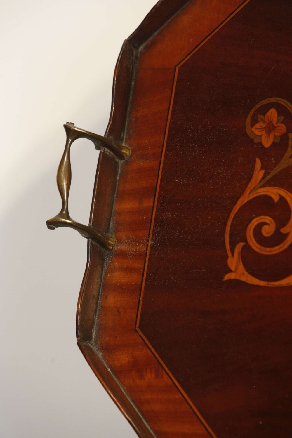 An octagonal mahogany serving tray featuring central marquetry inlay depicting twin winged griffins flanking a classical urn, with brass handles on two sides. View VIII
