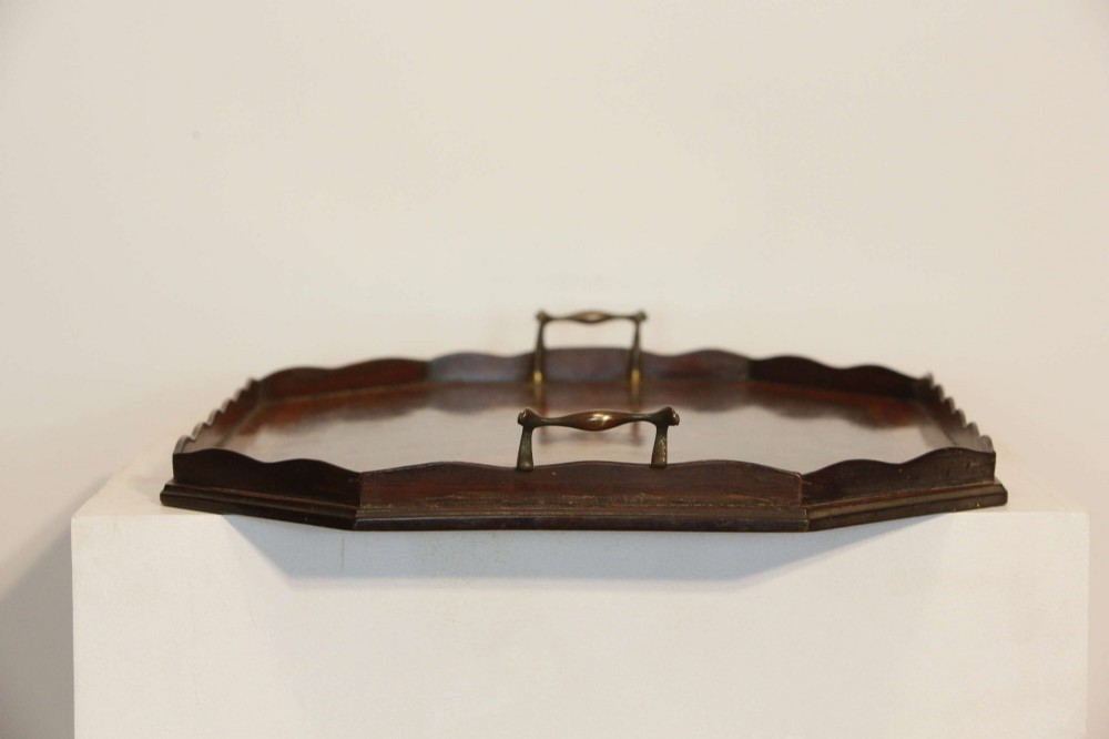 An octagonal mahogany serving tray featuring central marquetry inlay depicting twin winged griffins flanking a classical urn, with brass handles on two sides. View XII